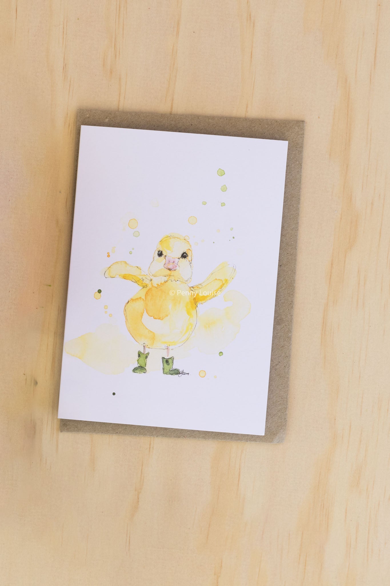 Card with a watercolor illustration of a duckling wearing boots on a wooden surface