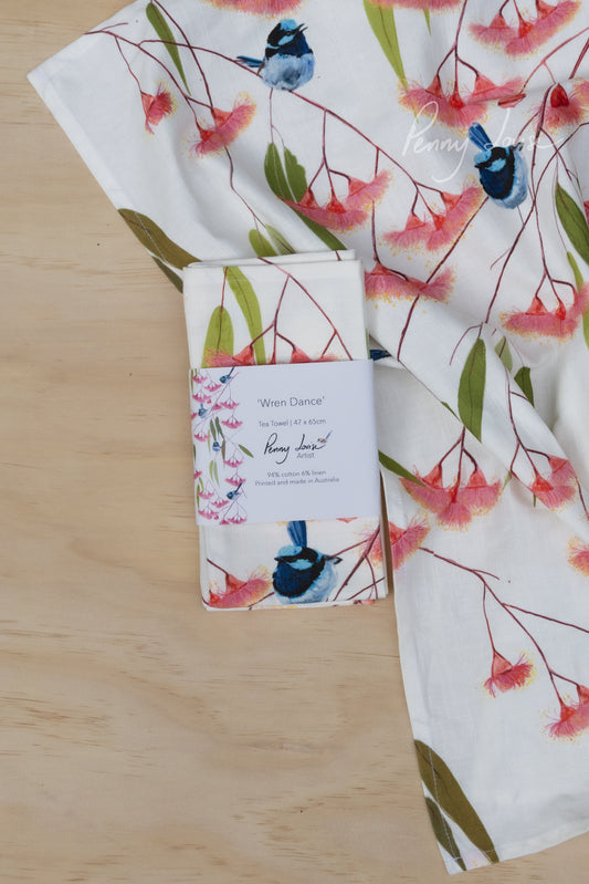 Floral and bird-patterned tea towel on a wooden surface